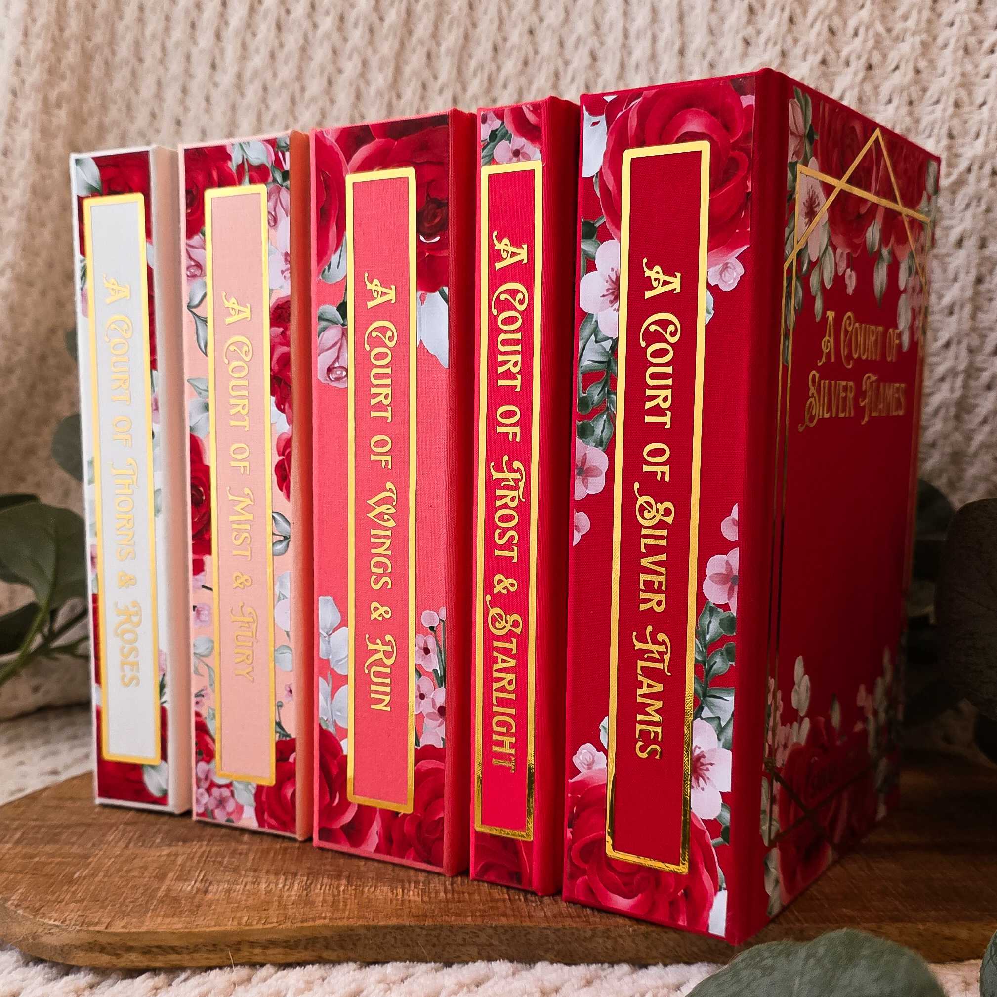 ACOTAR whole set with floral designs on white to red backgrounds.